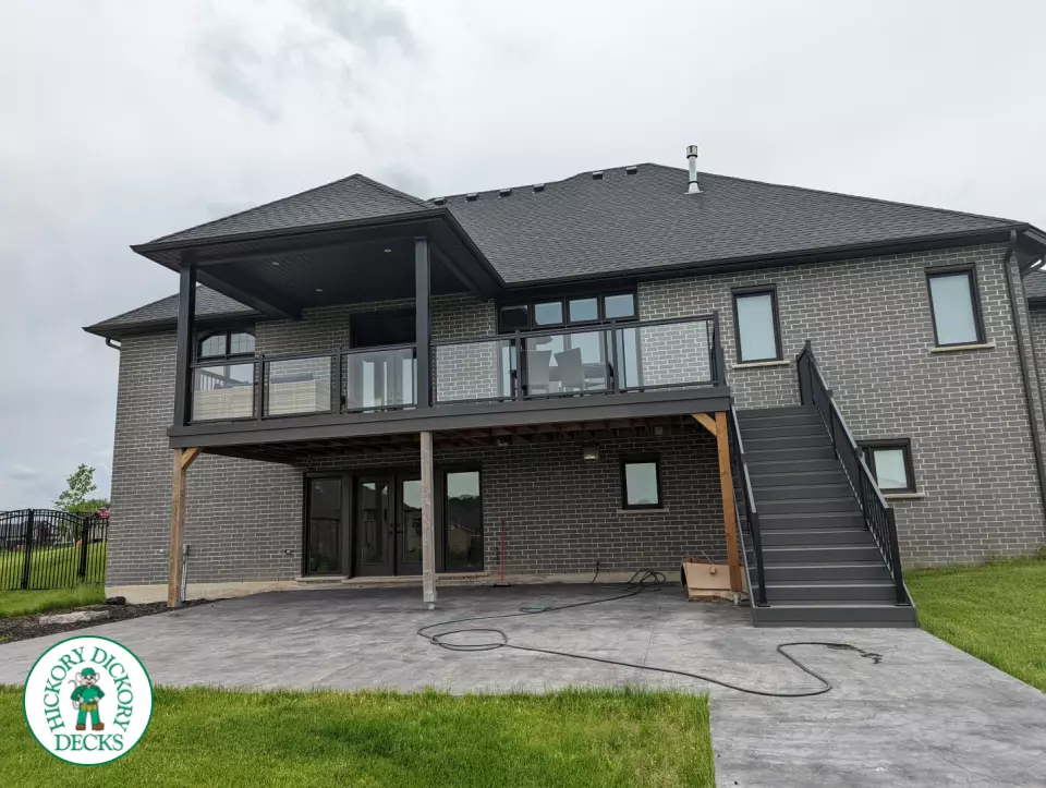 Large high grey trunorth deck with glass railings, and a custom roof structure.