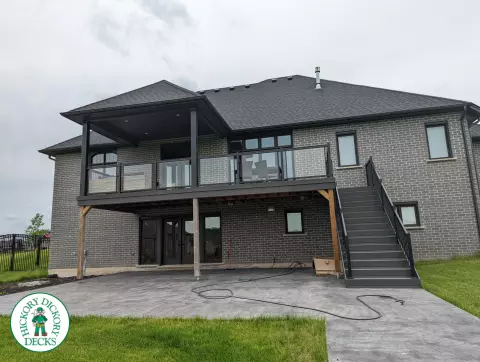 Large high grey trunorth deck with glass railings, and a custom roof structure.