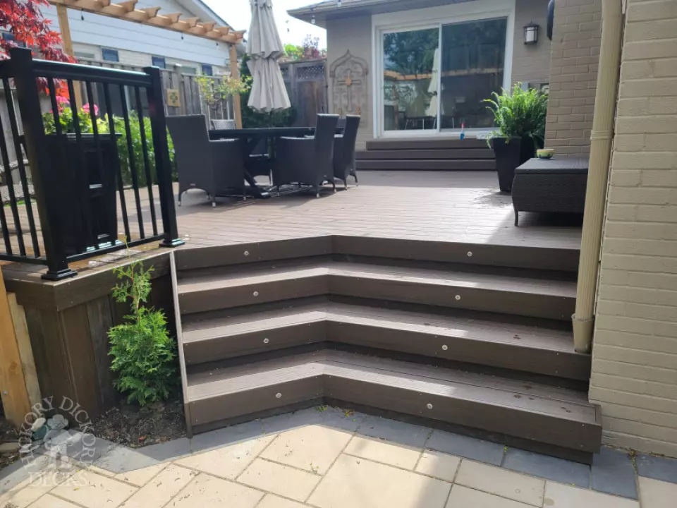 Large brown composite deck with pergola and unique stairs.
