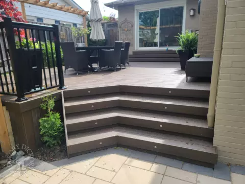 Large brown composite deck with pergola and unique stairs.
