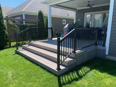 Small covered grey composite porch with aluminum railing.