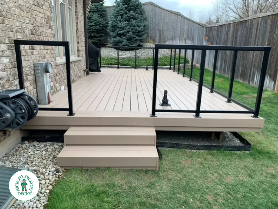 400 square foot beige composite deck with glass railings.