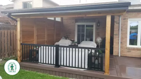 Low brown Veka deck with custom roof structure, black aluminum railing, and lights in steps.
