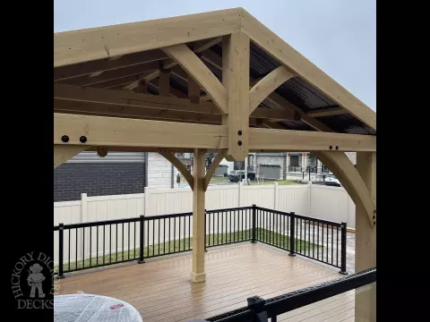 Brown composite deck with a roof structure, glass railings, access to the hot tub, and frosted glass privacy screens.