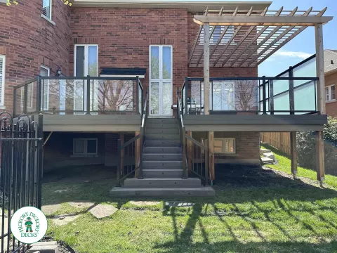 Large high deck with pergola, glass railing and frosted glass privacy screen.