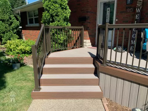 Grey front porch with brown trim and brown aluminum railing.