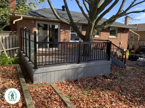 Clubhouse deck in colour driftwood built around a tree featuring: aluminum railings and frosted glass privacy screens, Mississauga, Ontario