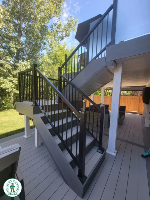 Multi level grey clubhouse deck with dark grey border and glass privacy screens on the top level.