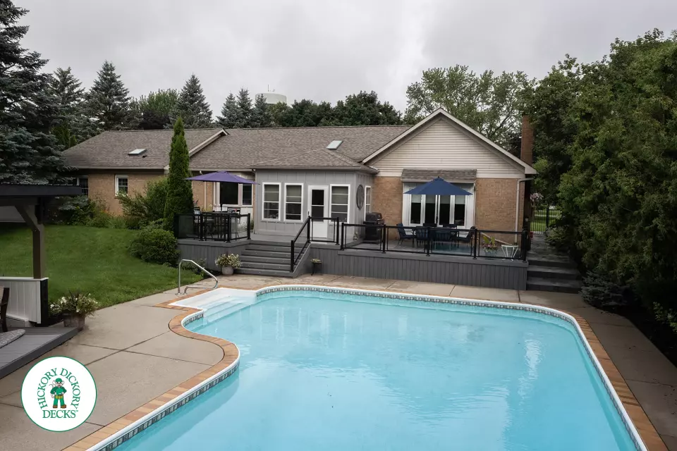 Large grey clubhouse deck with multi levels, lights in the steps, and glass railings.