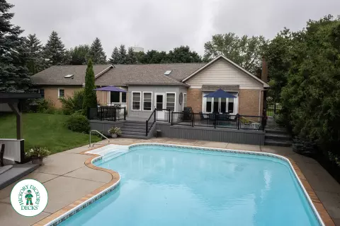 Large grey clubhouse deck with multi levels, lights in the steps, and glass railings.