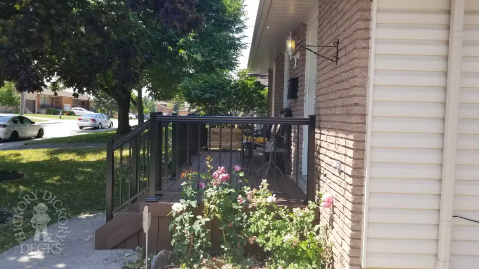 Small brown fiberon porch with black aluminum railing.