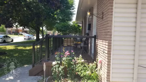 Small brown fiberon porch with black aluminum railing.