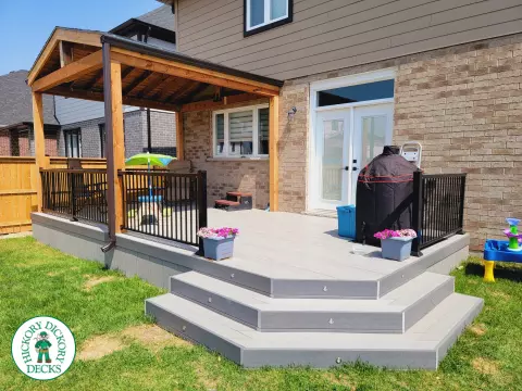 Large grey clubhouse deck with black aluminum railing and a custom cedar roof structure