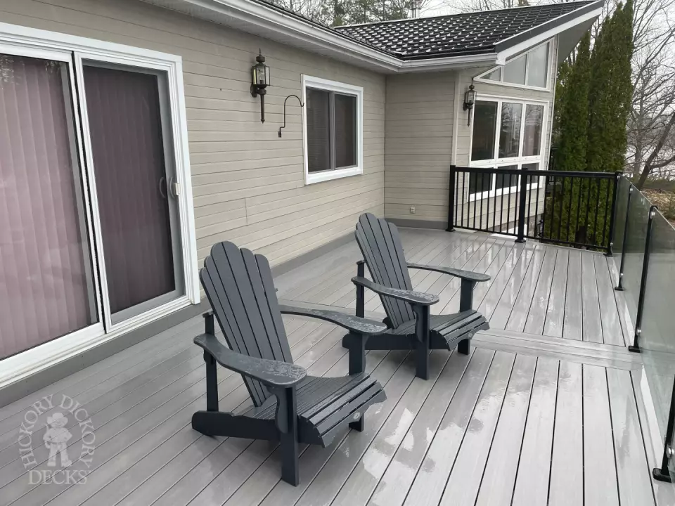 High grey fiberon deck with glass railings looking out to a lake.