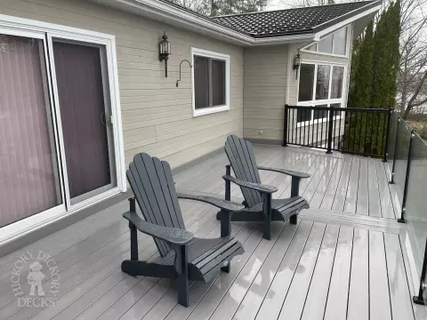 High grey fiberon deck with glass railings looking out to a lake.