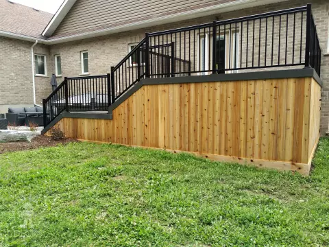 2 level clubhouse deck with cedar skirting, black aluminum railing, and grey color with darker grey border.