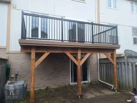 Dark brown Trex balcony with black aluminum railing.
