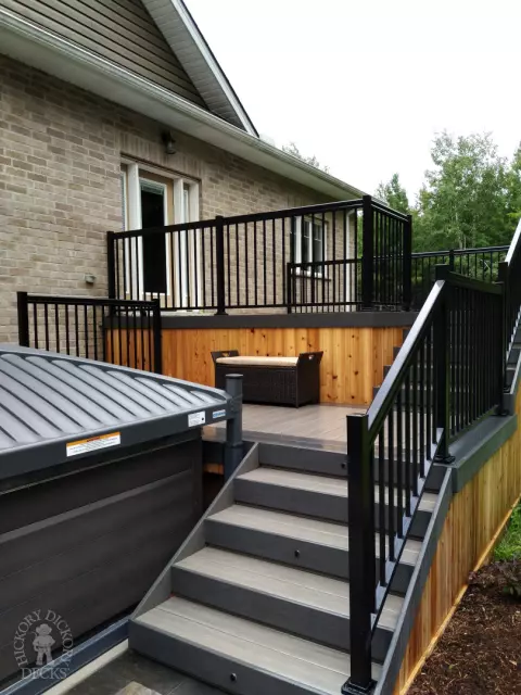 2 level clubhouse deck with cedar skirting, black aluminum railing, and grey color with darker grey border.