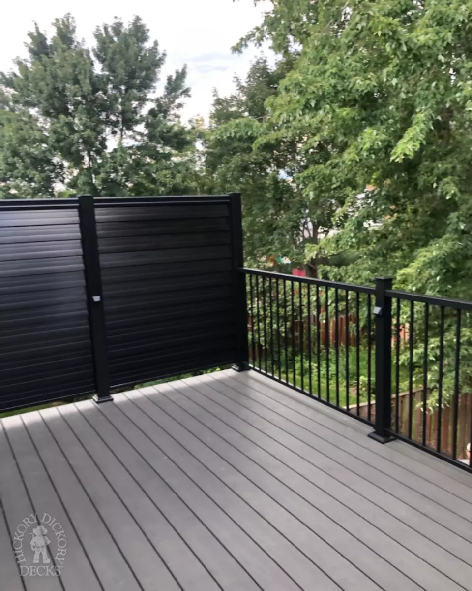 High clubhouse deck in dark grey with black aluminum railing and black privacy screen.
