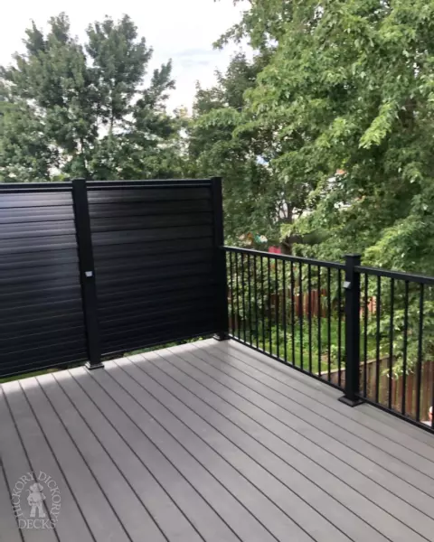 High clubhouse deck in dark grey with black aluminum railing and black privacy screen.