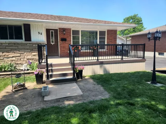 Large front porch in clay with a dark brown border and aluminum railings.