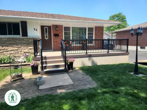 Large front porch in clay with a dark brown border and aluminum railings.