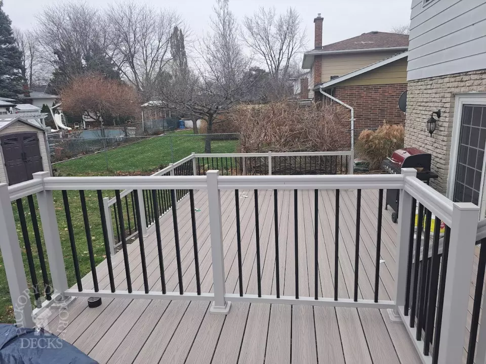 Two level grey Fiberon deck with beige picket aluminum railing and the top level surrounding an above ground pool.