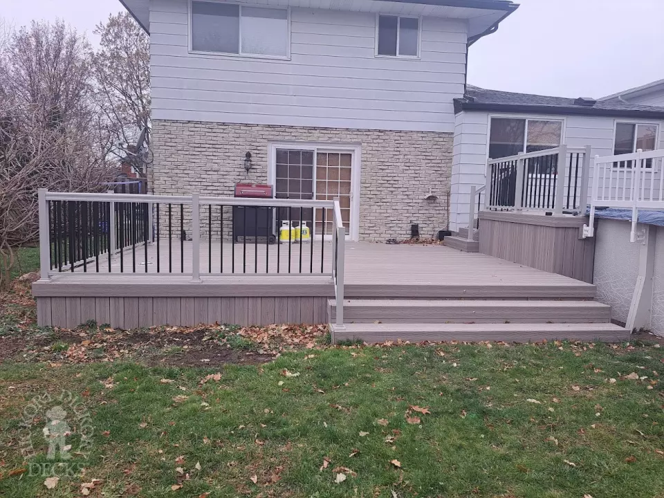 Two level grey Fiberon deck with beige picket aluminum railing and the top level surrounding an above ground pool.
