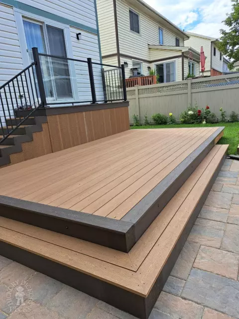 Multi level brown deck with glass railing, and a dark brown border.