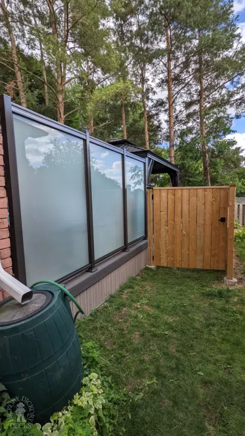 Grey composite walk out deck with dark grey borders, stained glass privacy screens, and aluminum style railing.