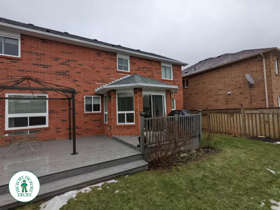 Grey composite deck with dark grey border, cedar skirt, and aluminum picket railing.