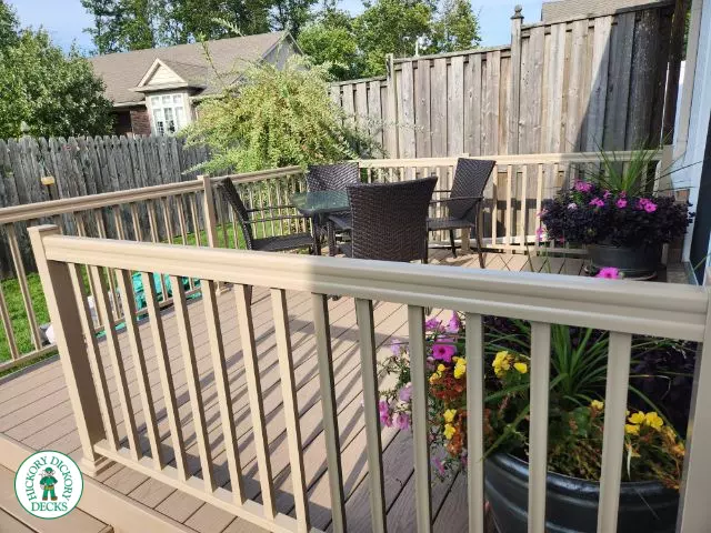 Small beige composite deck with beige railings, accessibility ramp into house.