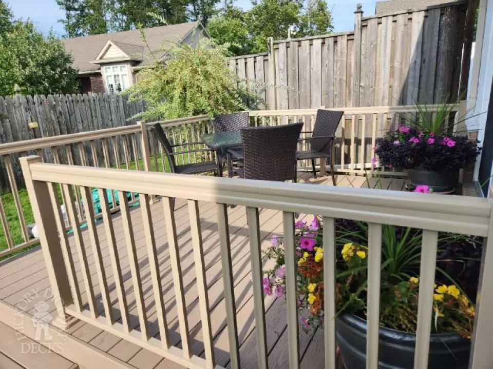 Small beige composite deck with beige railings, accessibility ramp into house.