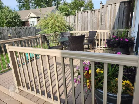 Small beige composite deck with beige railings, accessibility ramp into house.