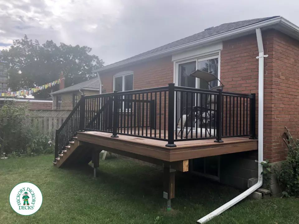 Small brown composite deck with 8 steps up and black aluminum railing.