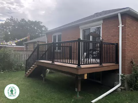 Small brown composite deck with 8 steps up and black aluminum railing.