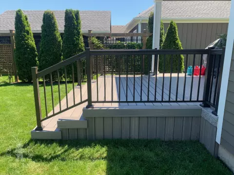 Small covered grey composite porch with aluminum railing.