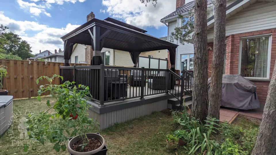 Grey composite walk out deck with dark grey borders, stained glass privacy screens, and aluminum style railing.