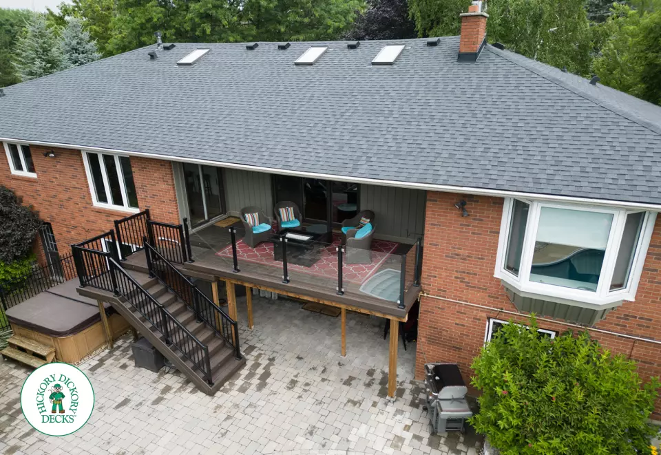 High brown deck with glass railings and lights in the stairs.