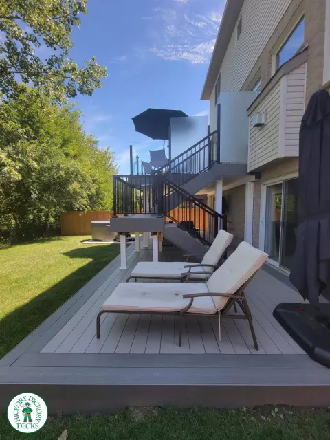 Multi level grey clubhouse deck with dark grey border and glass privacy screens on the top level.