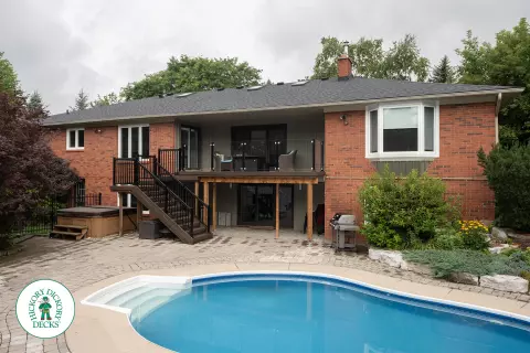 High brown deck with glass railings and lights in the stairs.