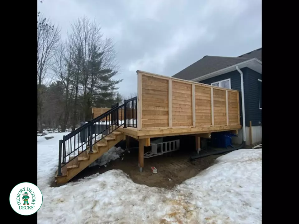 Cedar deck with stairs leading to walk out deck with aluminum railing and a cedar privacy screen.