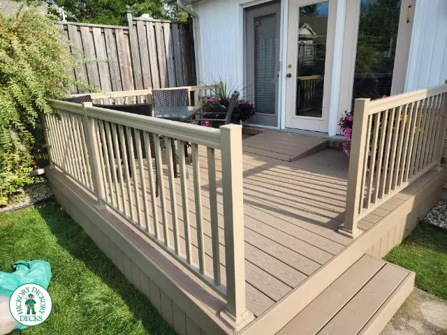 Small beige composite deck with beige railings, accessibility ramp into house.