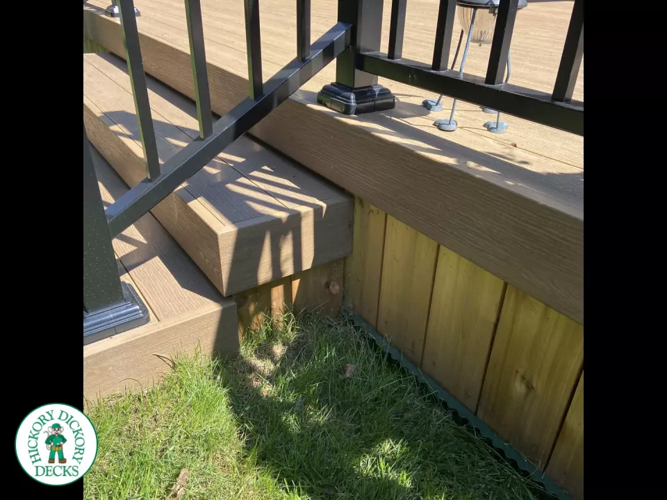 3 steps leading to small brown clubhouse deck with black aluminum railing.