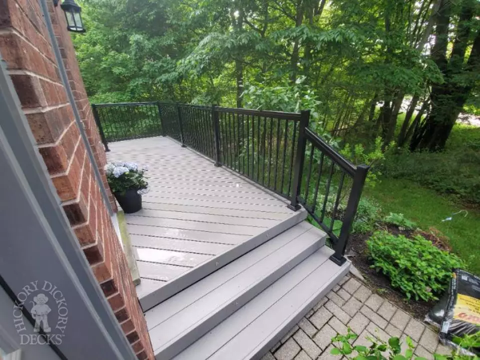 Small grey mid-rise composite deck with cedar posts.