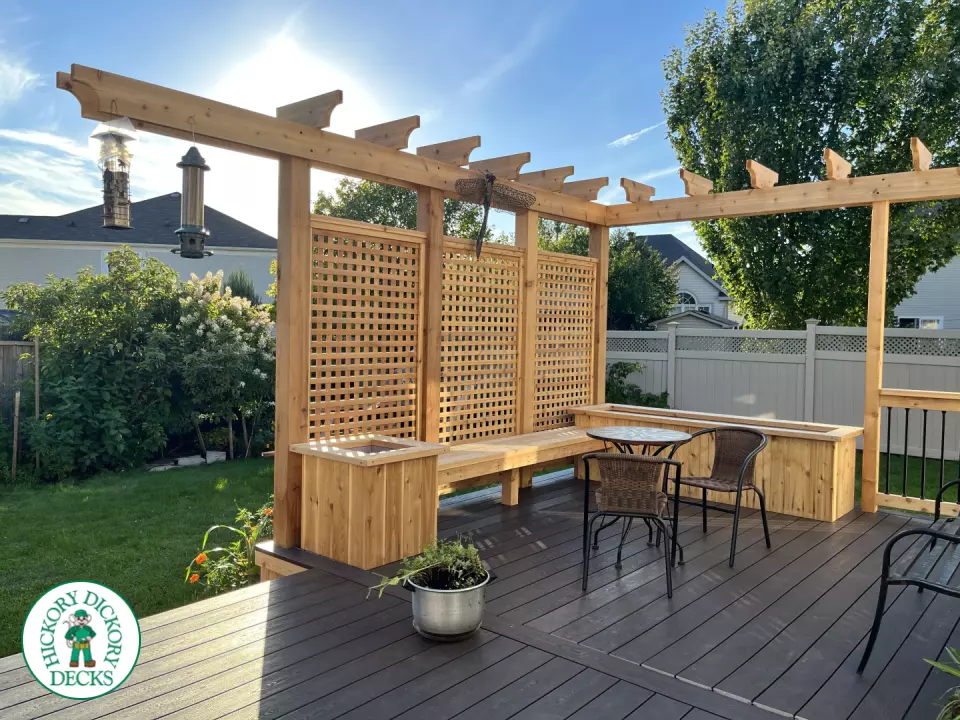Mid size clubhouse deck in brown with cedar skirt, benches, planters, and a pergola.