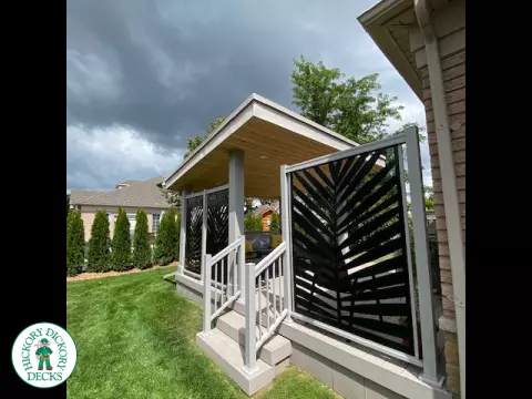 Low, small Azek deck with two steps up, lights in stairs, a custom privacy screen and a custom roof structure.