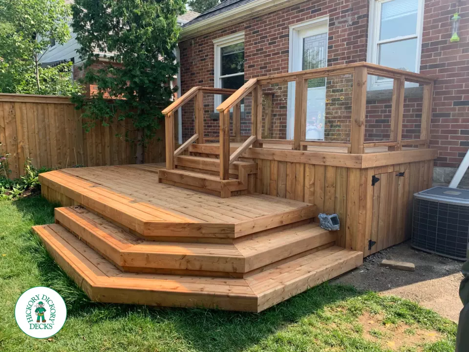 Small pressure treated deck with glass rail and a gate in skirt for storage.