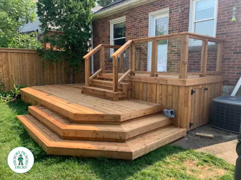 Small pressure treated deck with glass rail and a gate in skirt for storage.