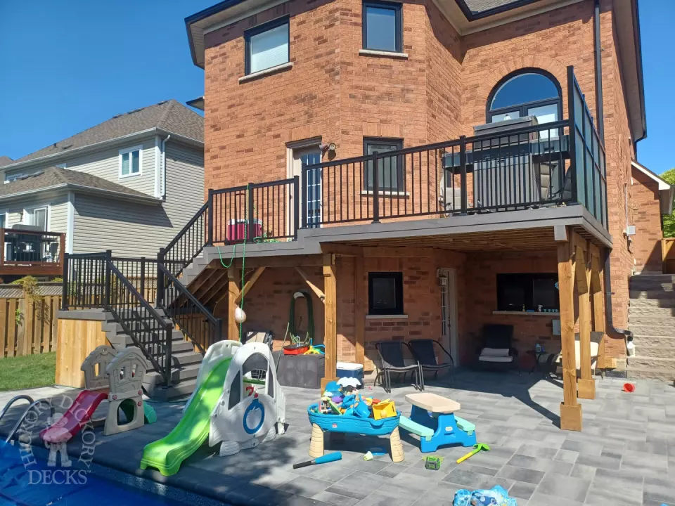 Large multi level grey composite deck with cedar skirt and black aluminum railing.
